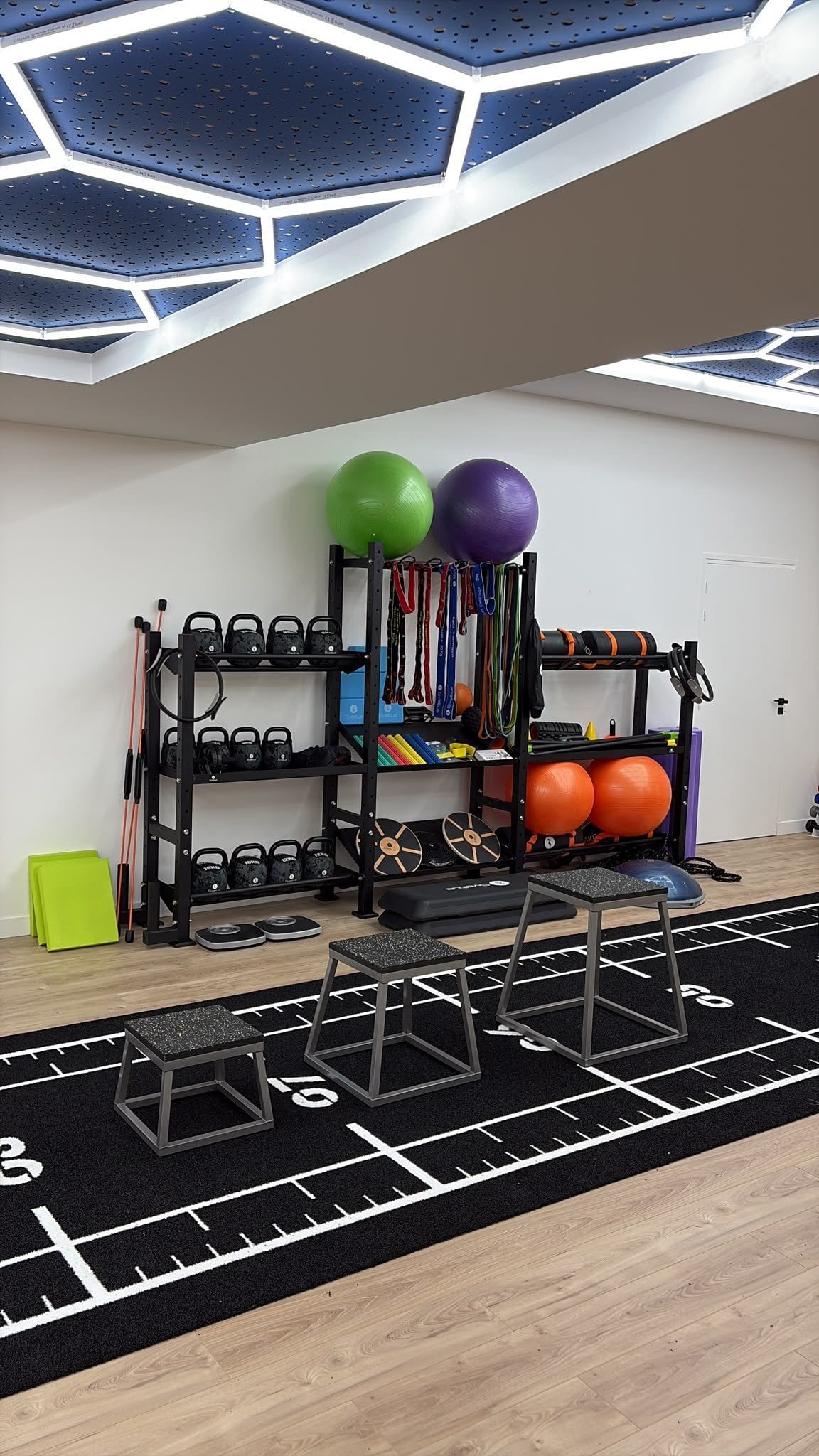 Rangement du matériel de renforcement : kettlebells, élastiques, ballons et plyo box sur la piste d’entraînement